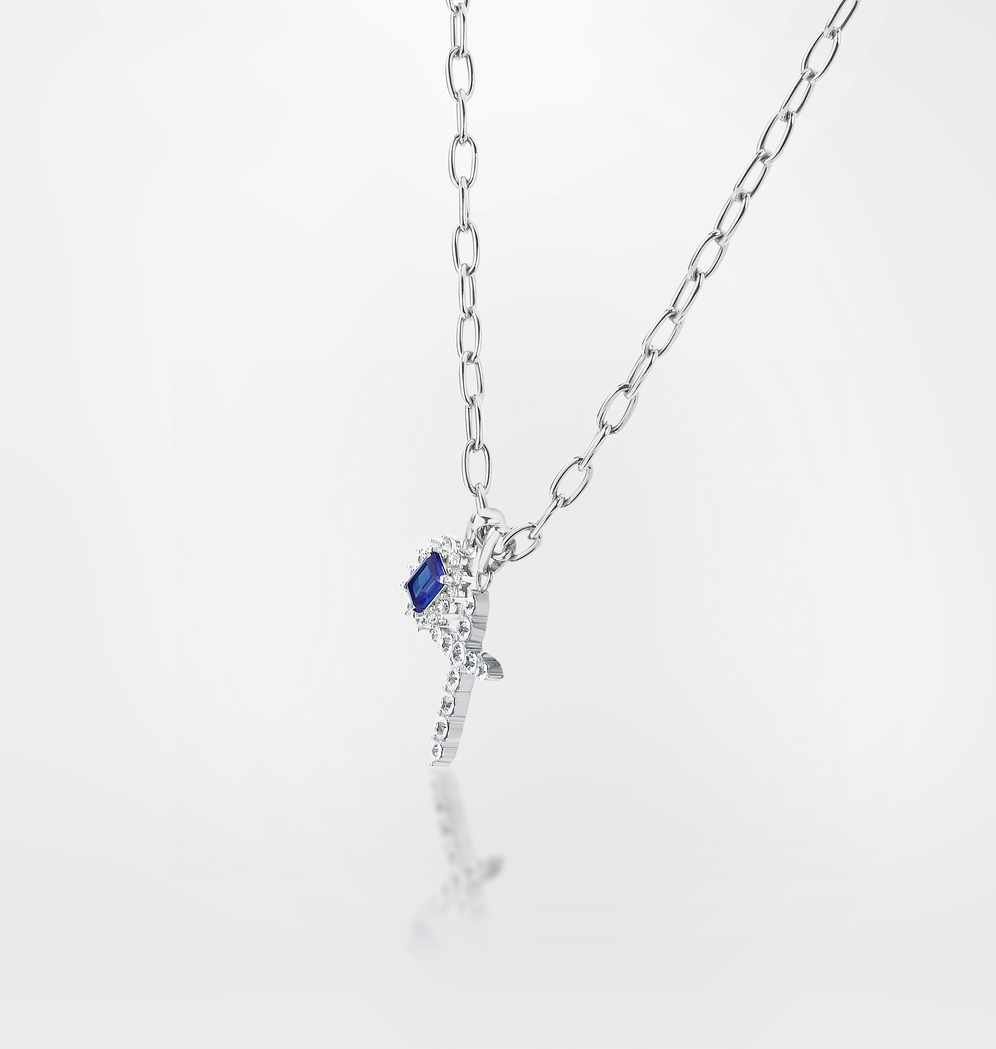 Silver chain detail with dangling cross charm
