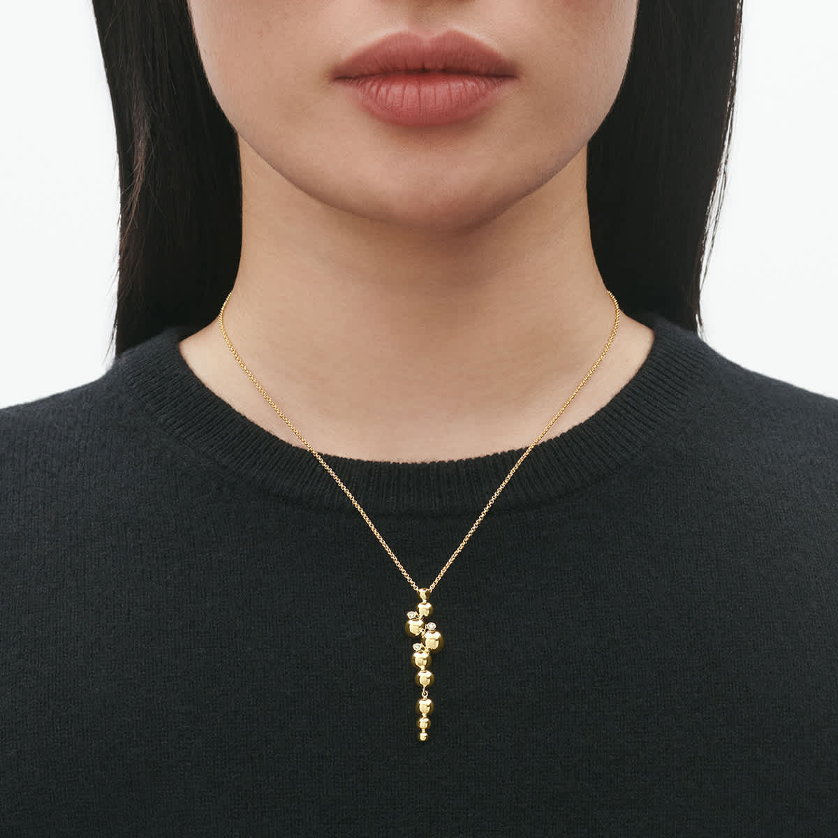 Long pendant worn high on a minimal black neckline