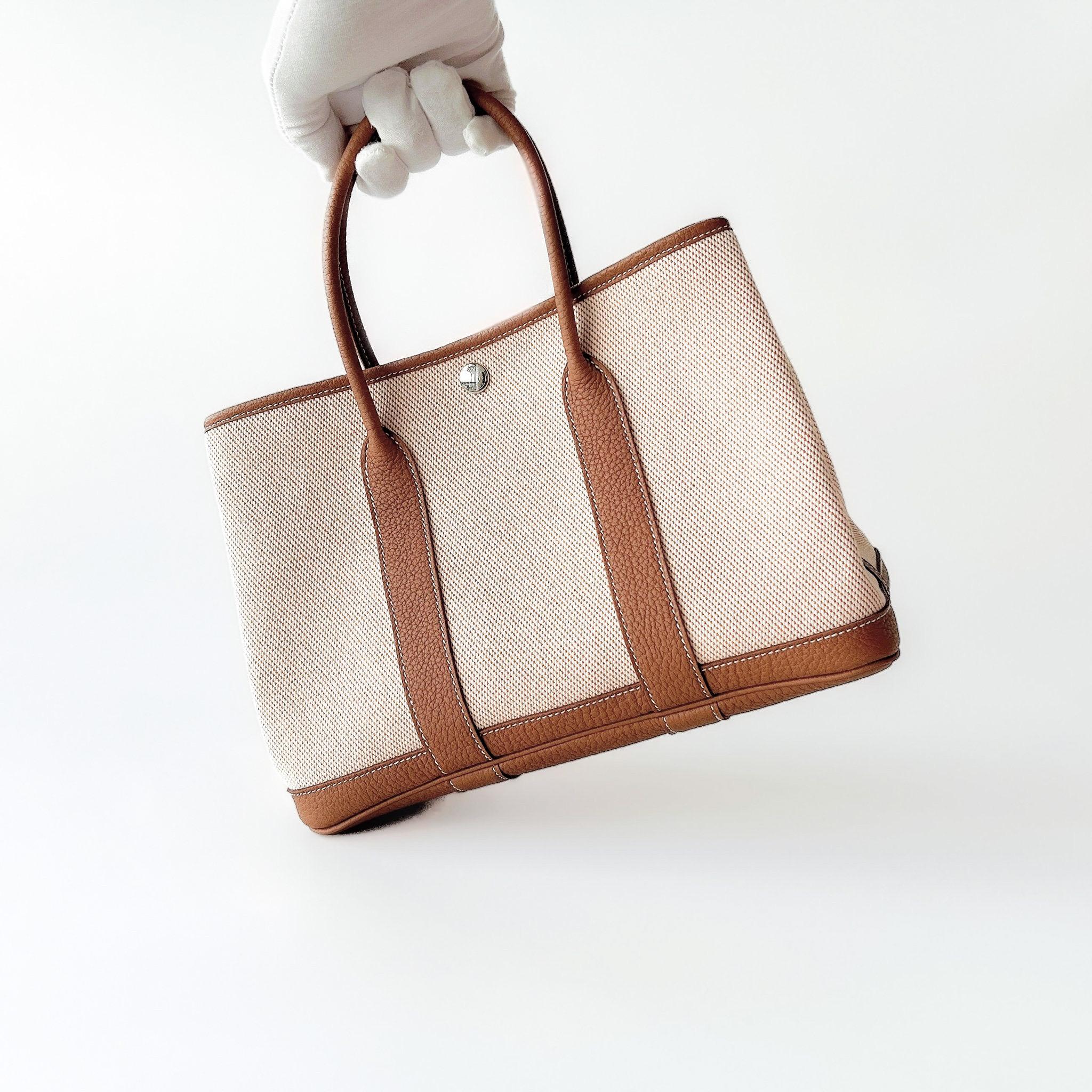Ecru canvas and tan leather Garden Party carried by the handles