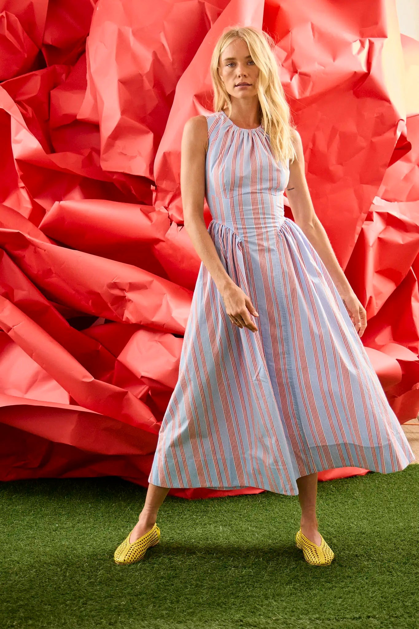 Full-length stance against the red set backdrop
