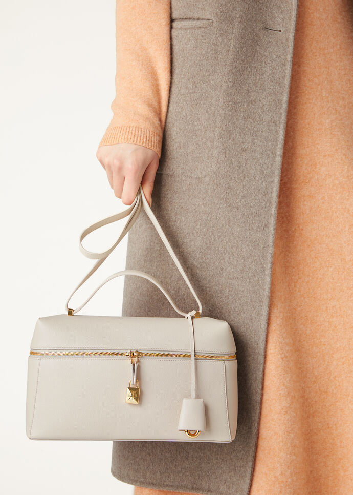 Carried by hand against a camel coat — scale view