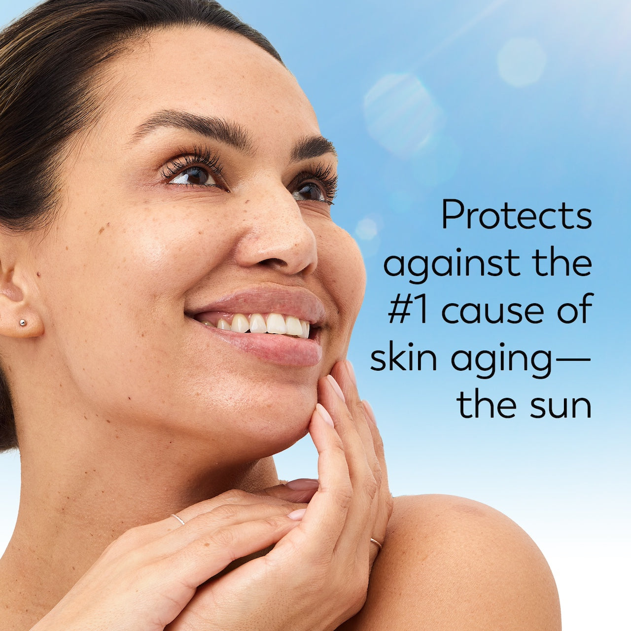Model posing and smiling. Protects against the #1 cause of skin aging. The sun.