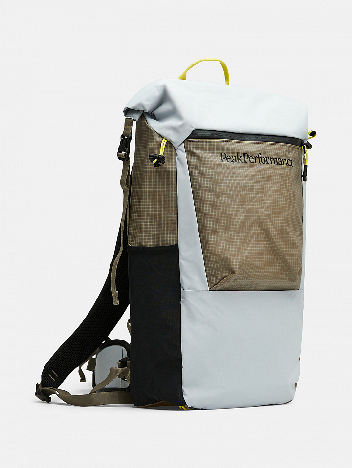Roll-top backpack in light gray and taupe with a black side panel, yellow accents, and “Peak Performance” text on the front pocket.