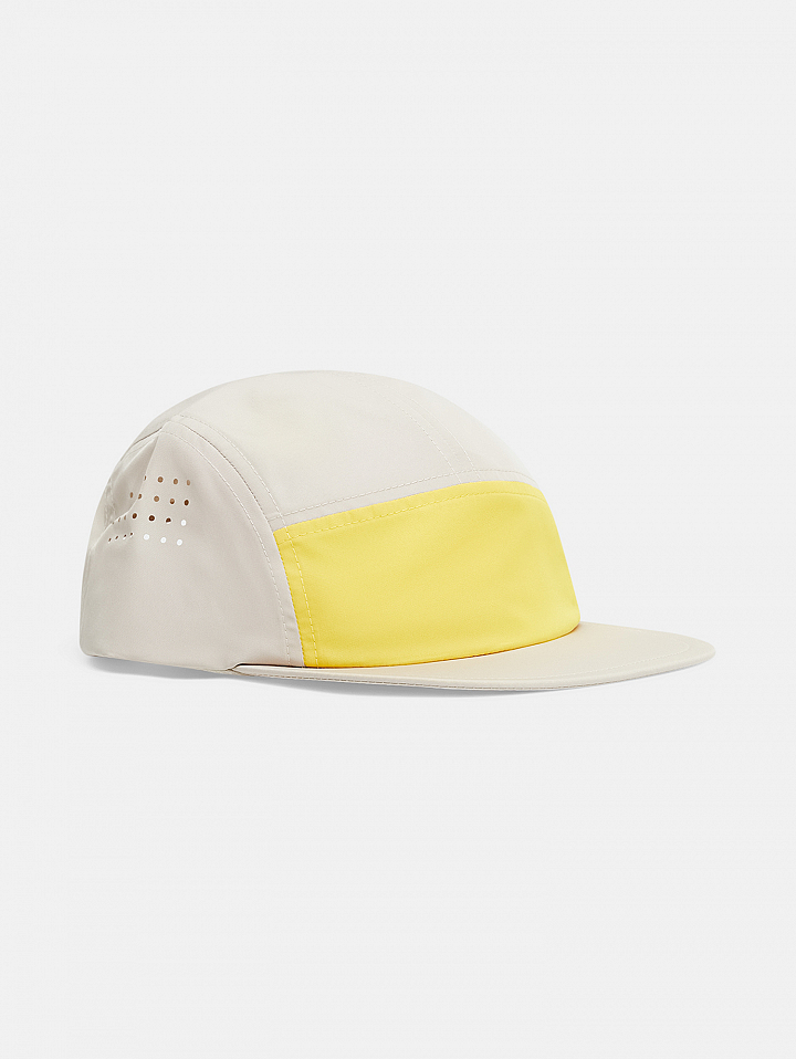 Side view of a cream-colored cap with a flat brim, yellow front panel, and small perforated ventilation holes on the side.