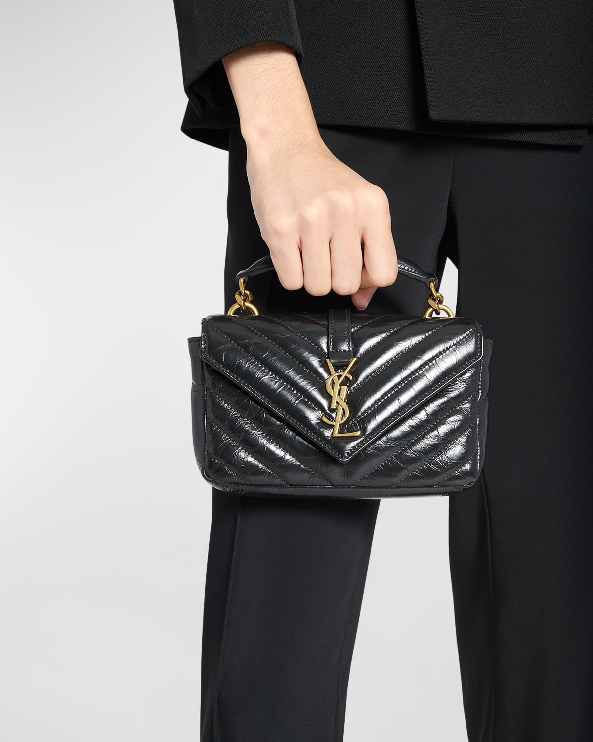 Mini carried by the top handle — the compact crossbody proportion