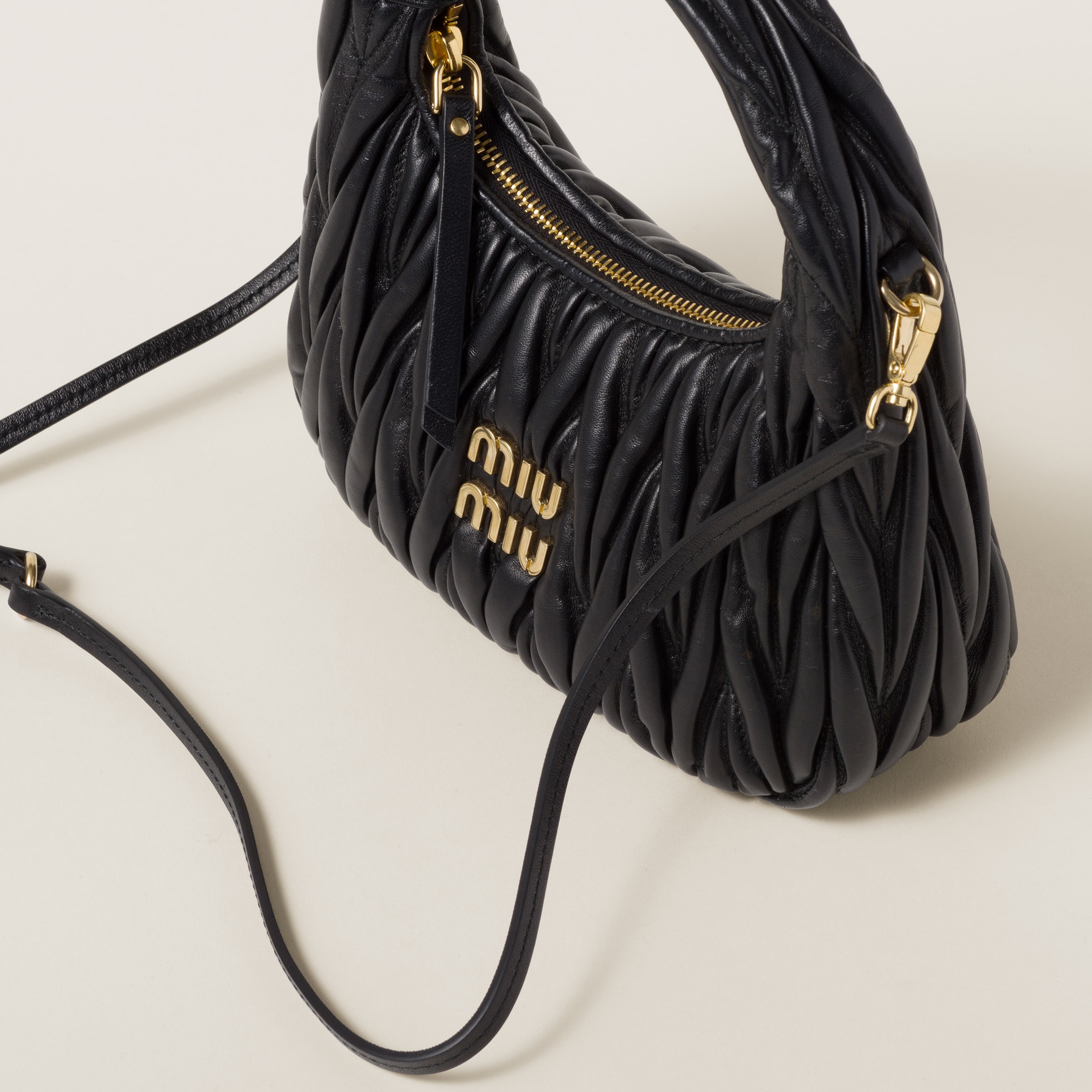 Close detail of Miu Miu Wander matelasse nappa leather, zipper closure, gold-tone hardware, and strap attachment.