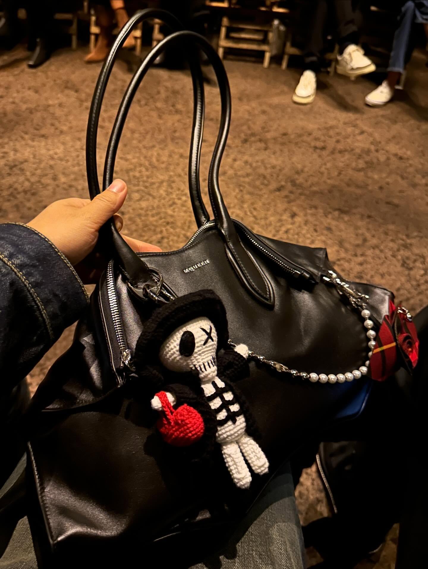 Alexander McQueen Manta Bag in black carried by hand with charms, source @mrbagss