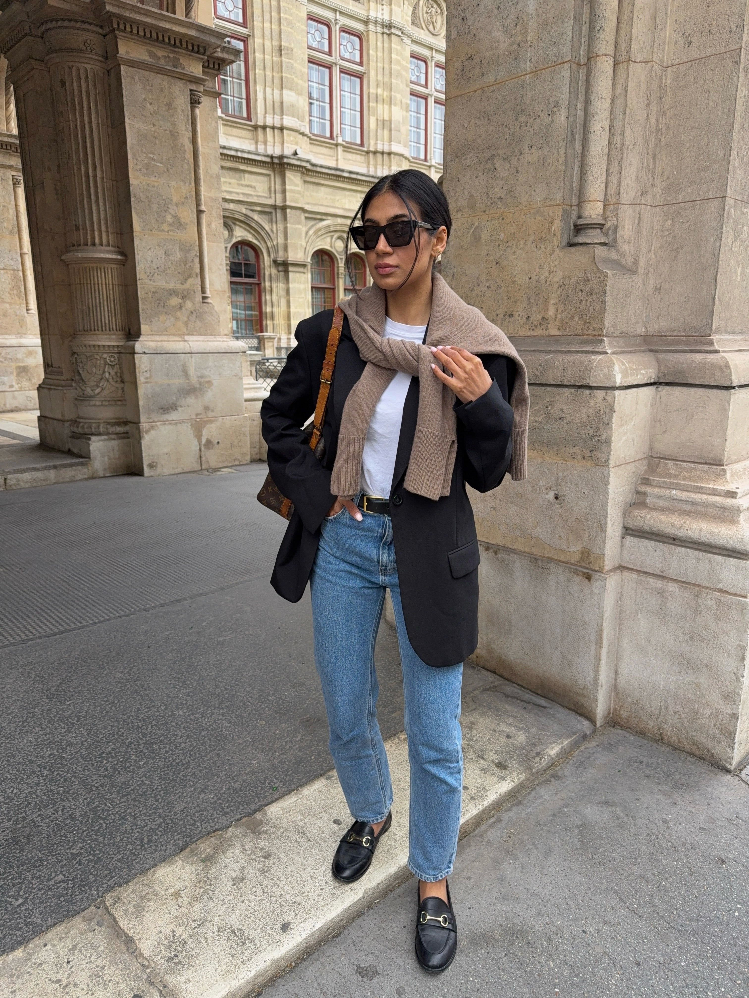 Complete weekend outfit with a black blazer, white tee, blue jeans, shoulder-draped knit, and loafers