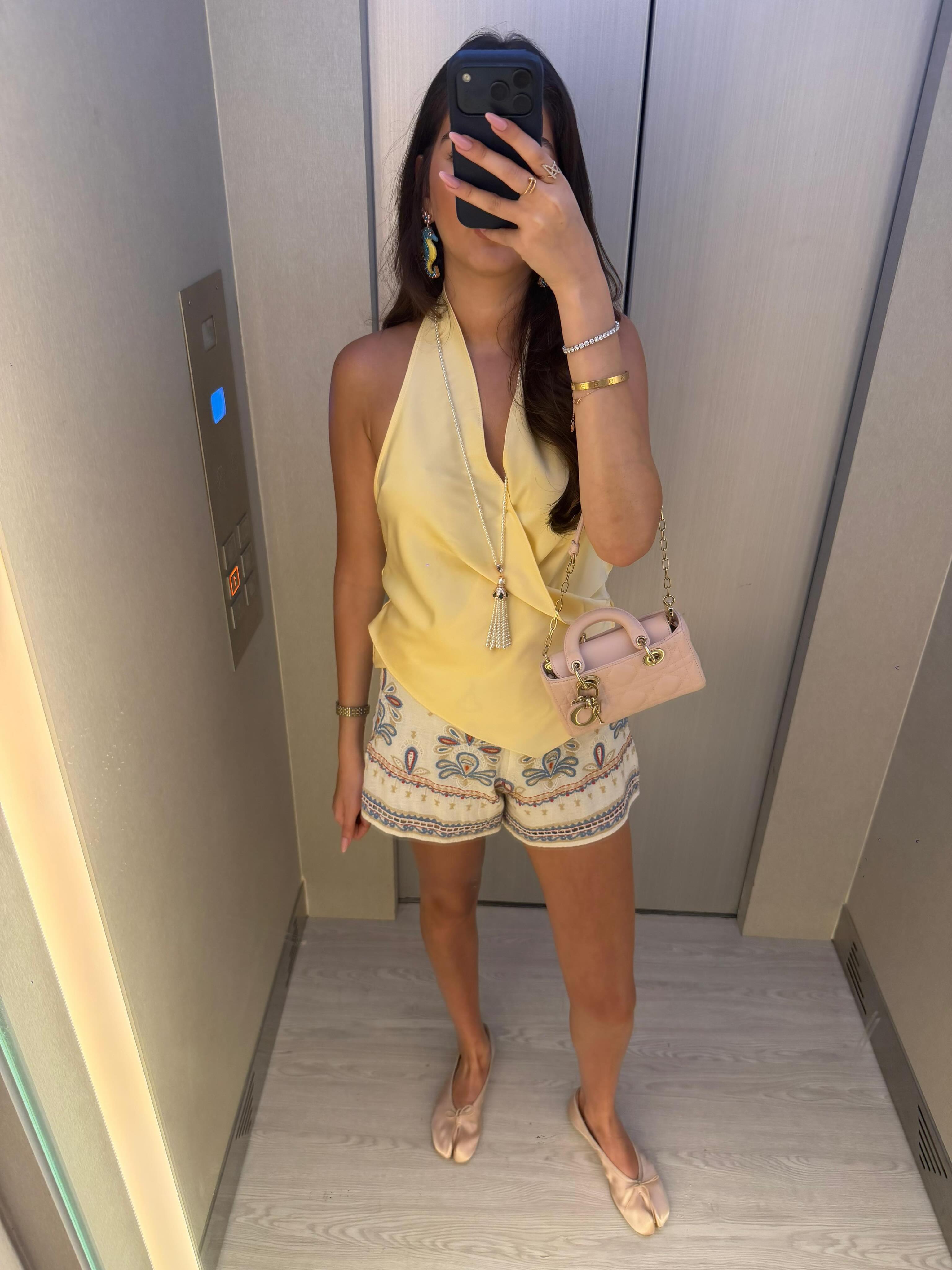 Full outfit with a long pearl-tassel necklace, halter top, printed shorts, and ballet flats