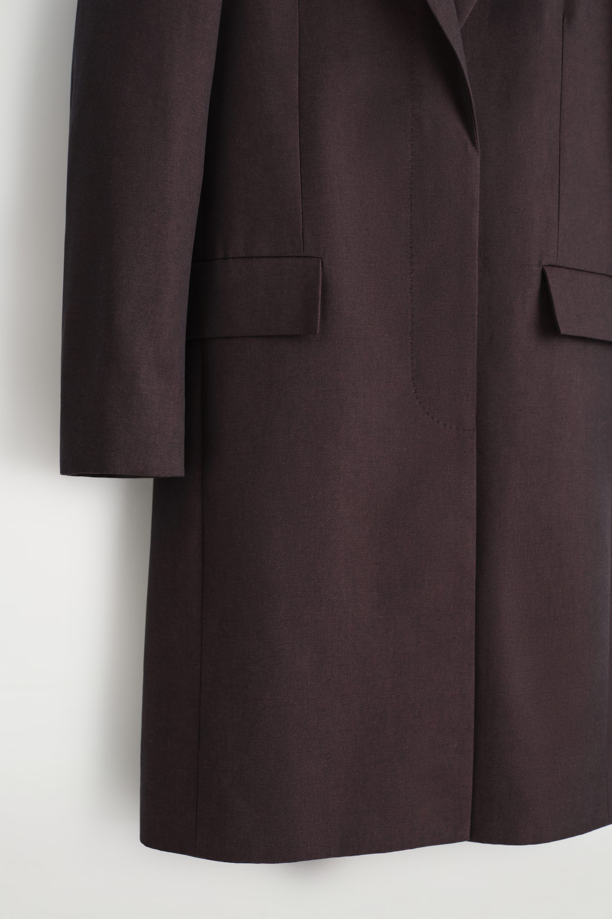 Close view of the burgundy COS coat pocket and hem