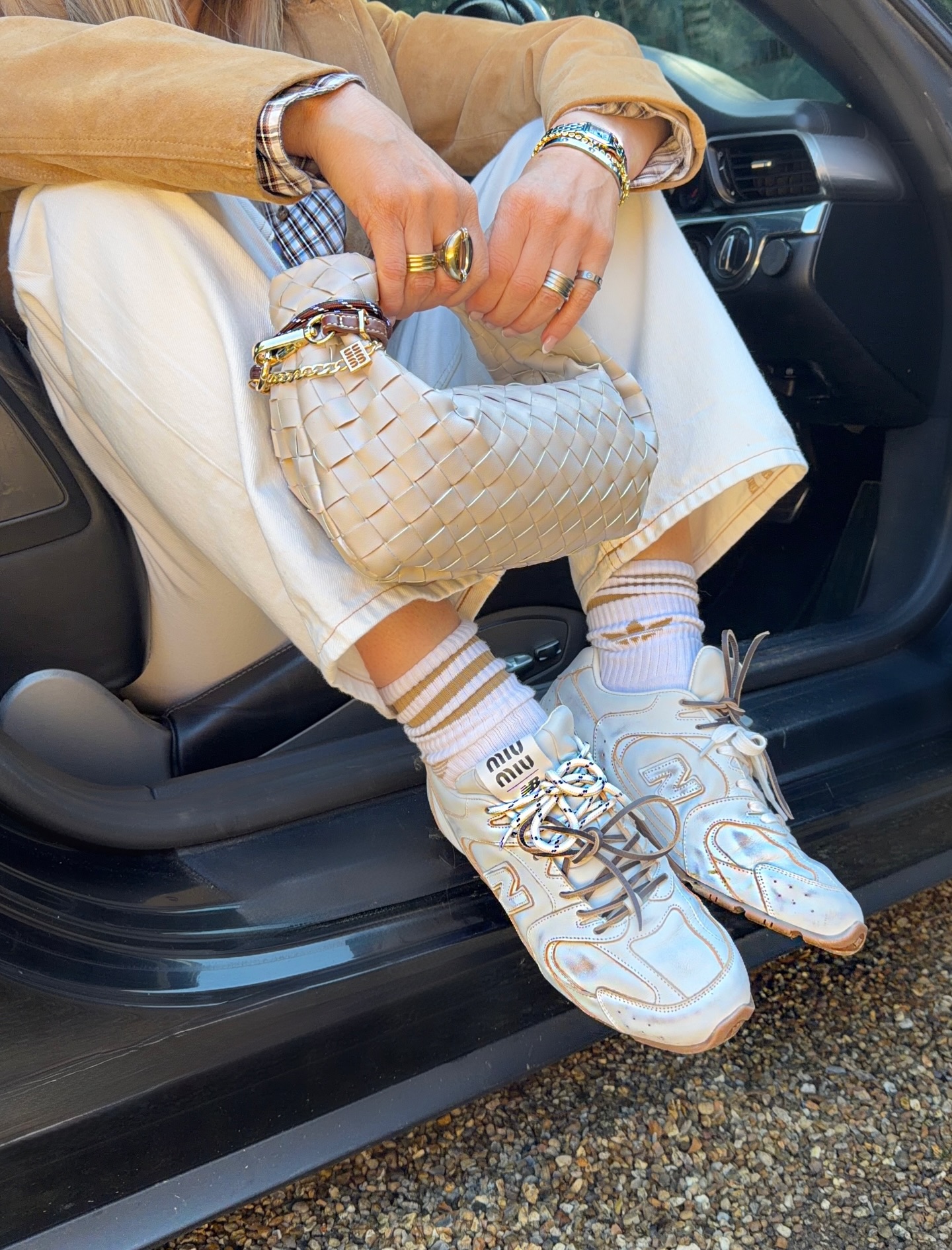 Close outfit detail of a cream woven Bottega Jodie bag with white jeans and sneakers
