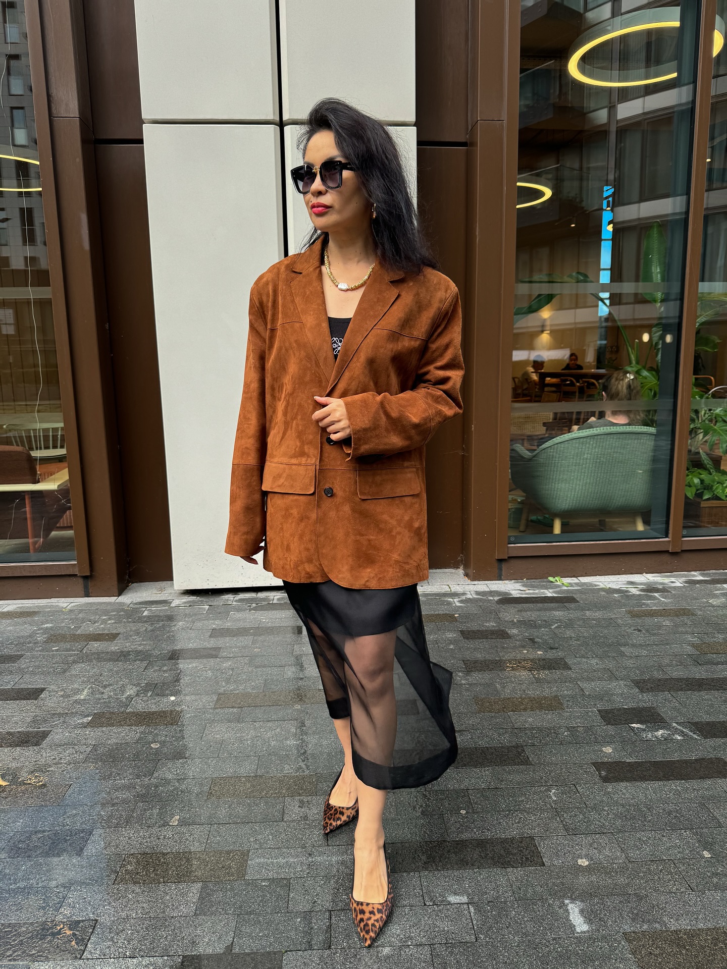Woman in a complete brown suede blazer and black sheer midi skirt outfit