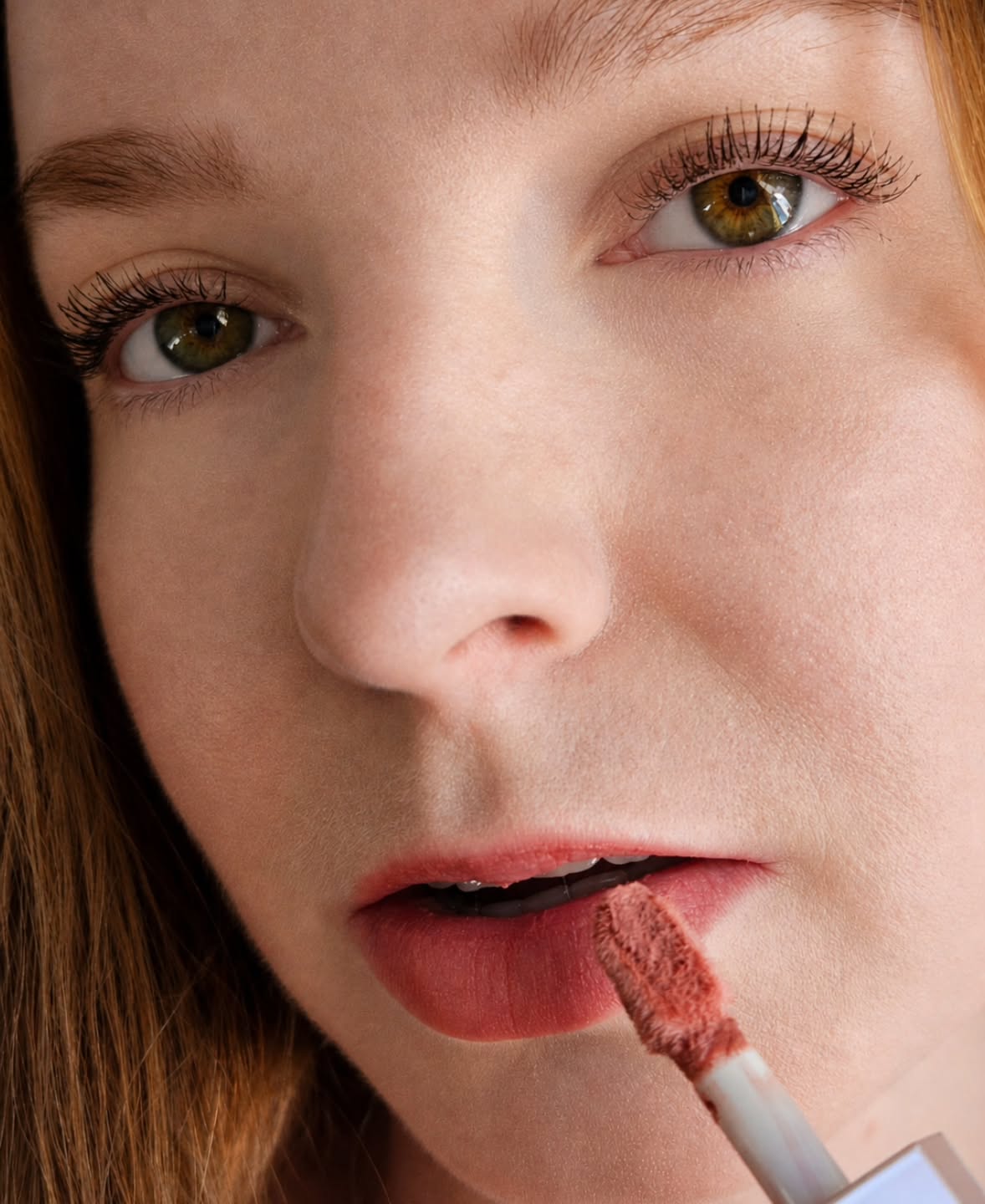 Close portrait of @ksyuugc applying rose lip color with a wand