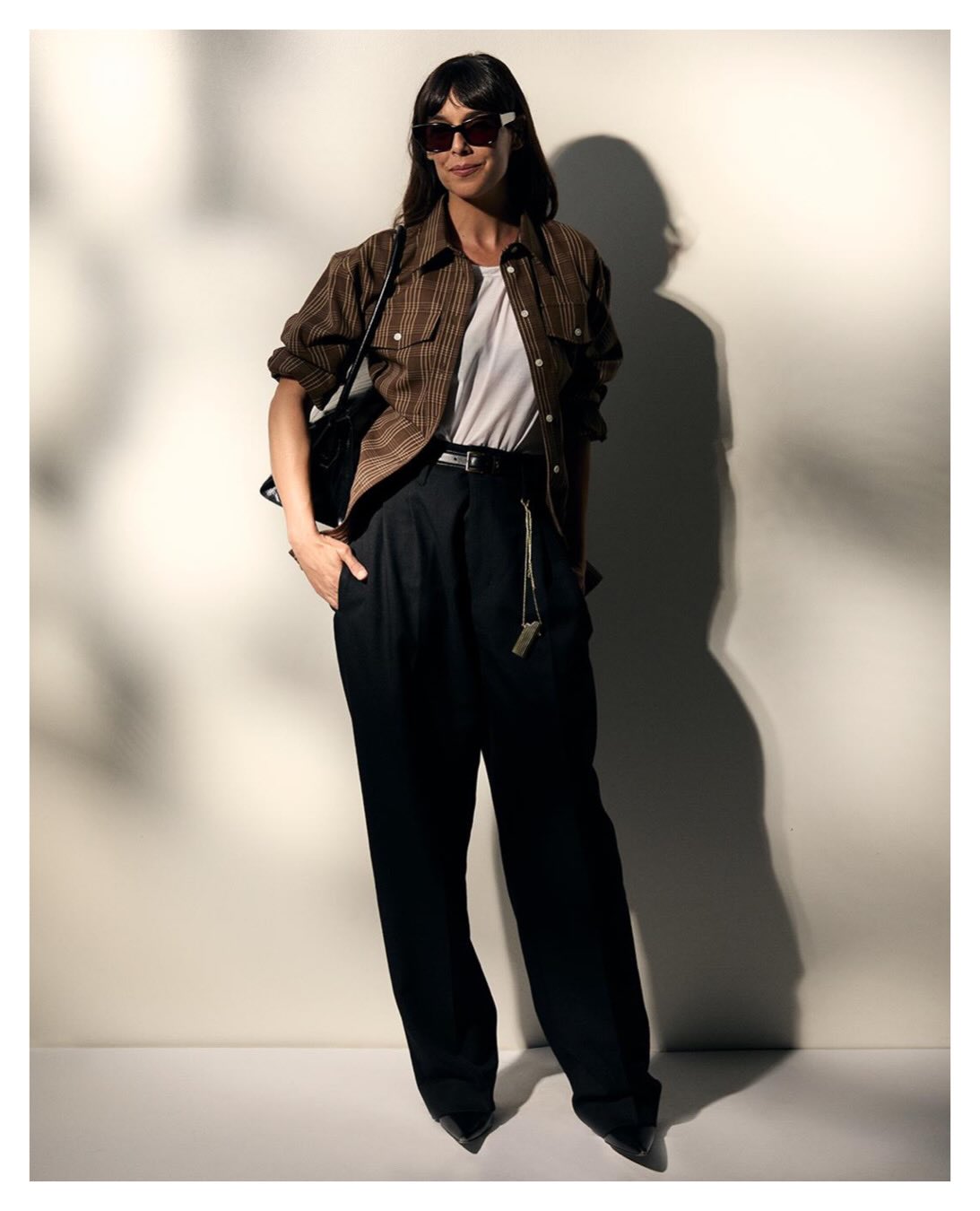Woman wearing a checked overshirt, white tee, and wide black trousers