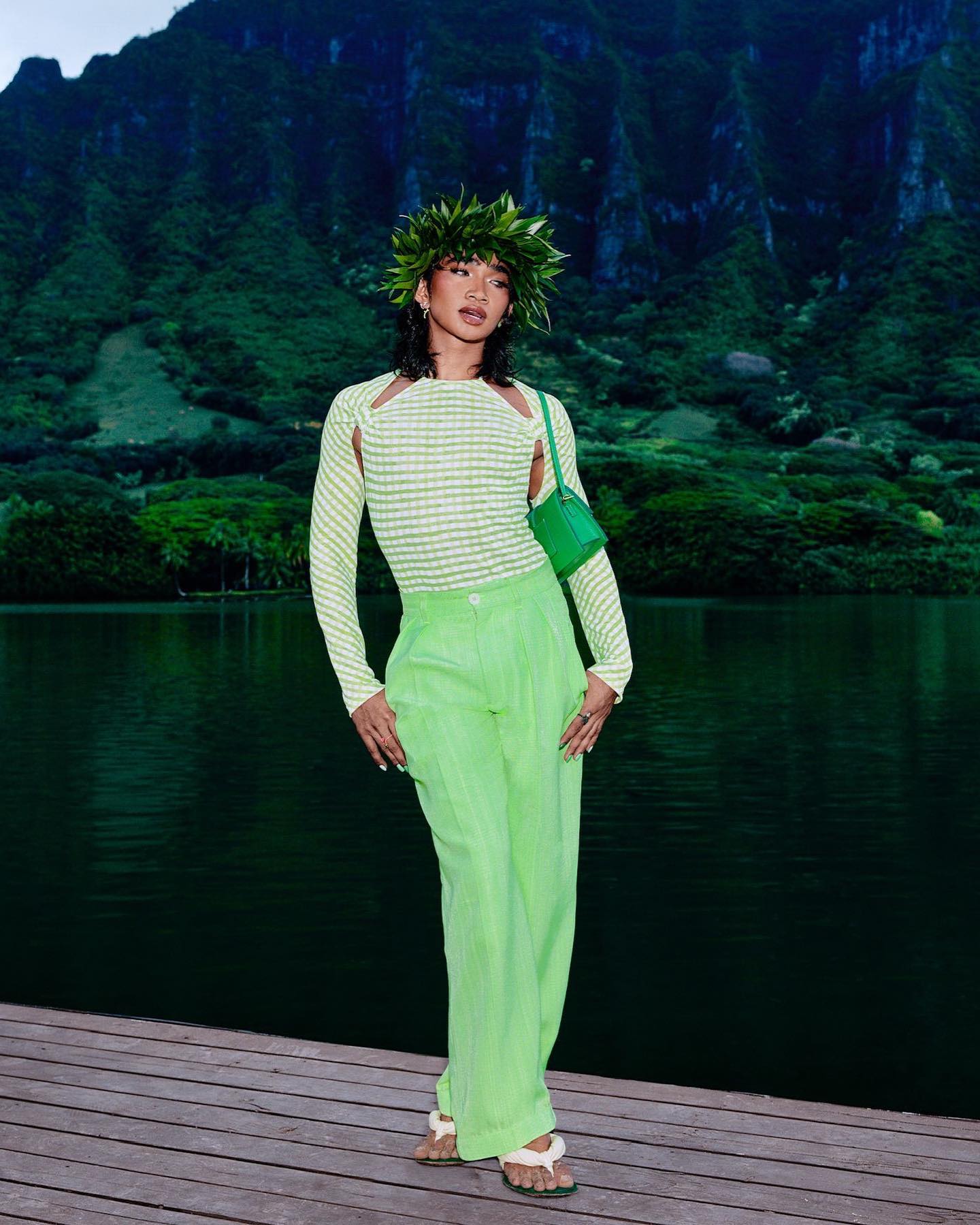 Bretman Rock wearing green Jacquemus styling by the water with a small green shoulder bag.