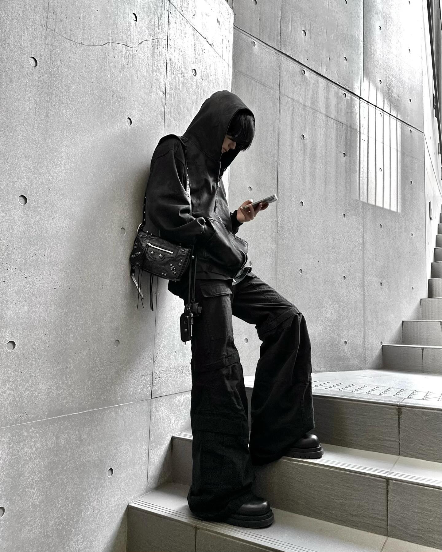 Person styling a black Balenciaga Le Cagole with an all-black streetwear outfit