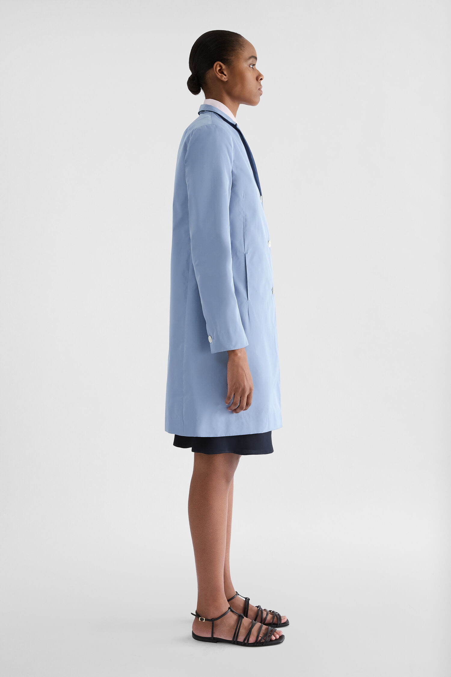 Jil Sander Radzimir Coat side view on a model, pale blue technical fabric, straight profile, and buttoned cuff visible.
