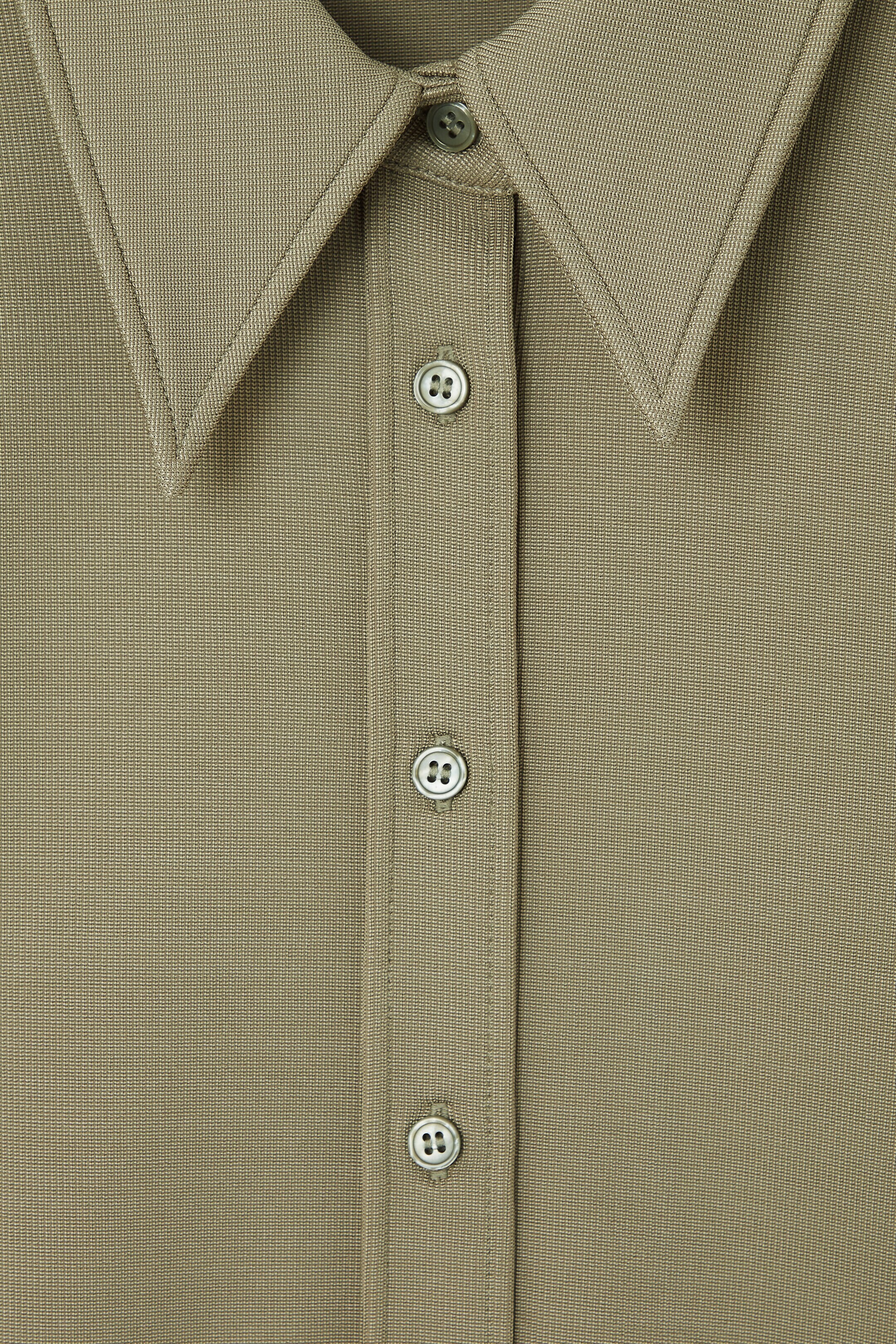 Close view of COS pale olive jersey shirt with exaggerated collar and buttons