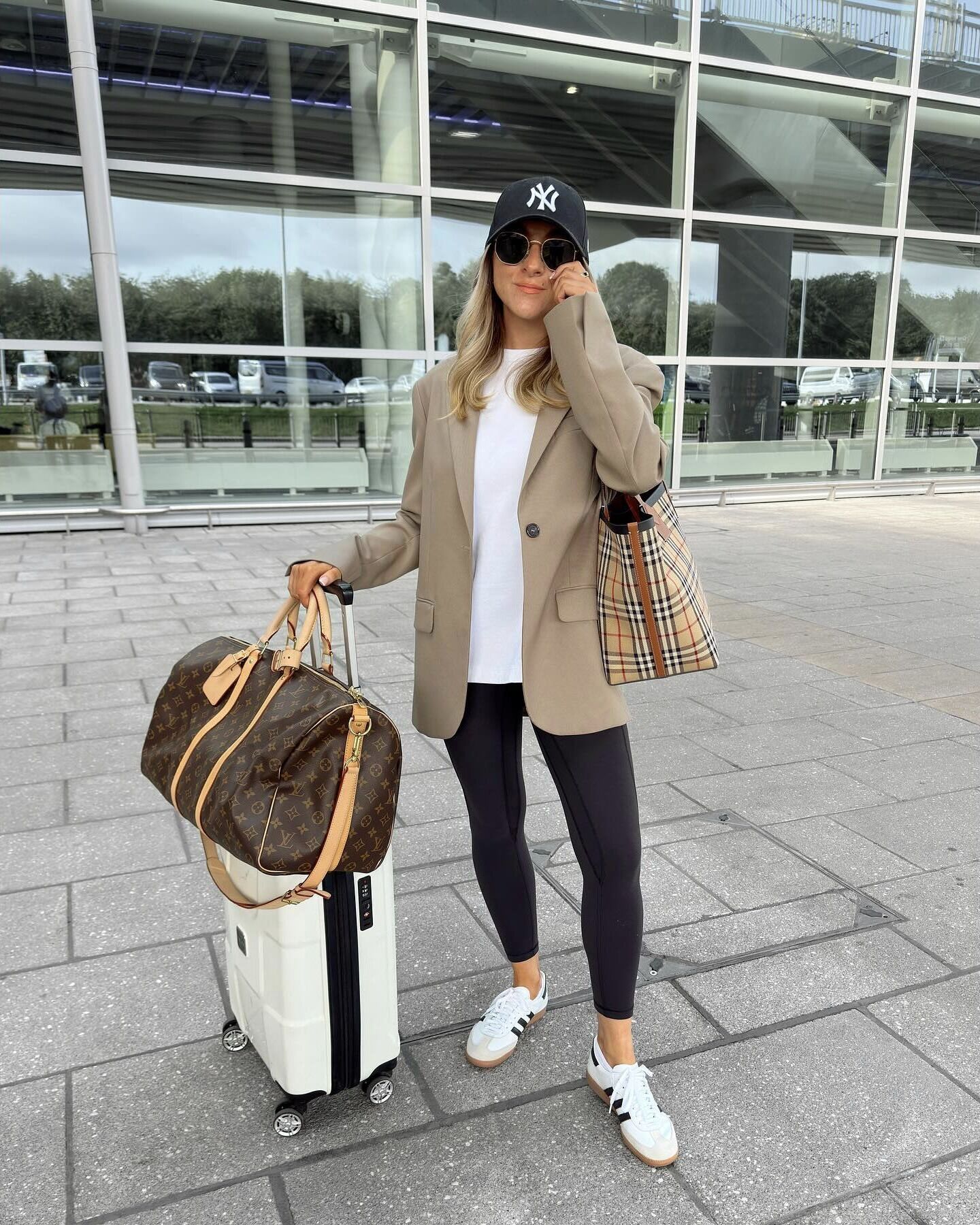 Traveler wearing a taupe blazer over a white T-shirt with black leggings and white sneakers