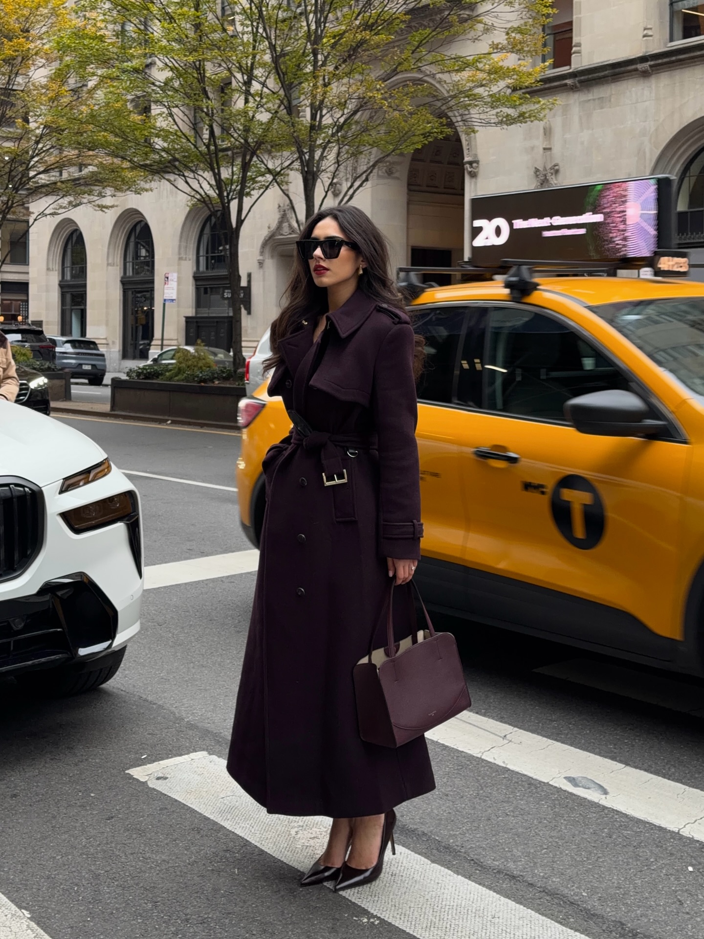 Creator @imhrisa wearing a burgundy ankle-length coat closed with its matching self-belt, pointed pumps, and a tonal bag
