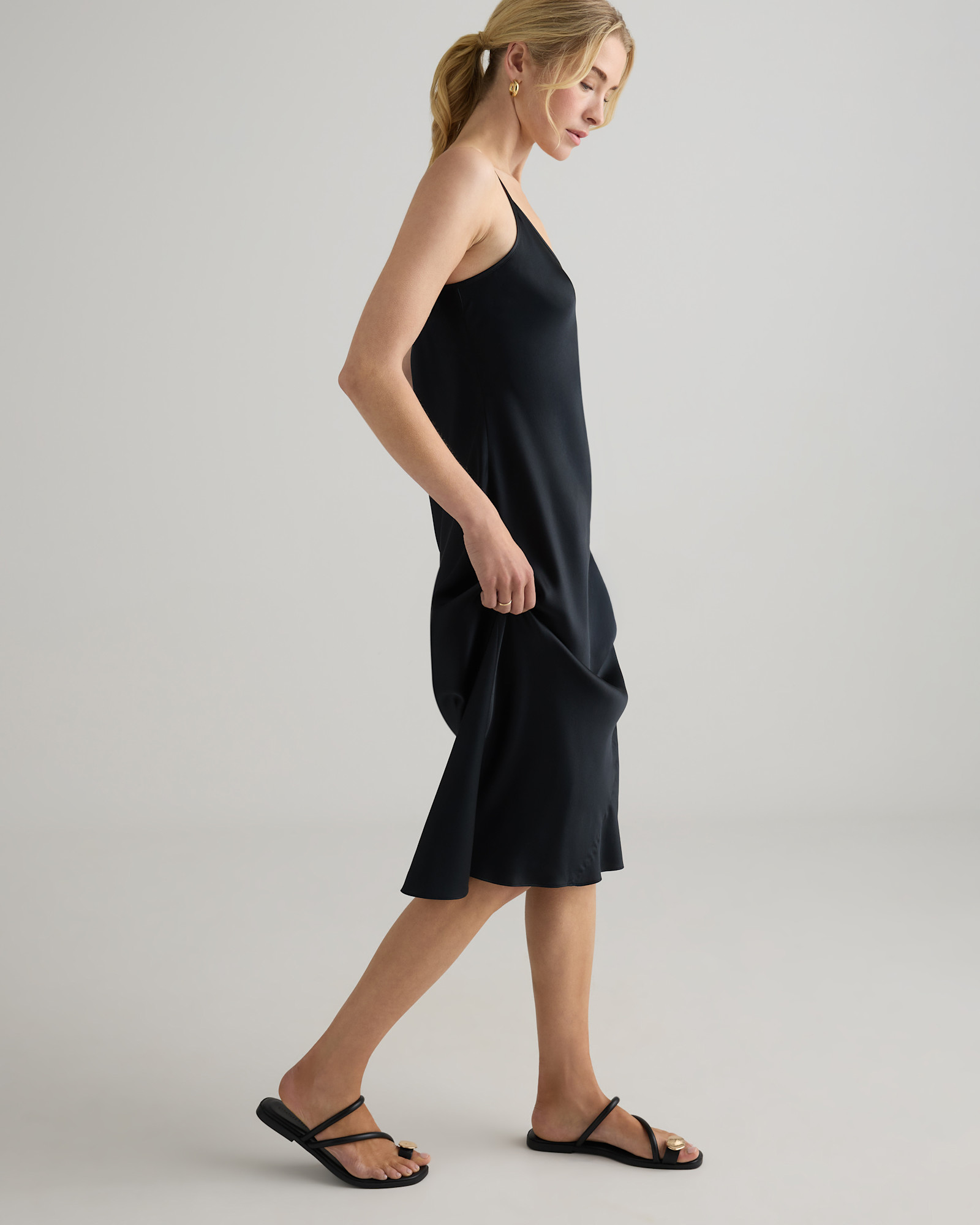 Model wearing the Quince black silk slip dress in side profile