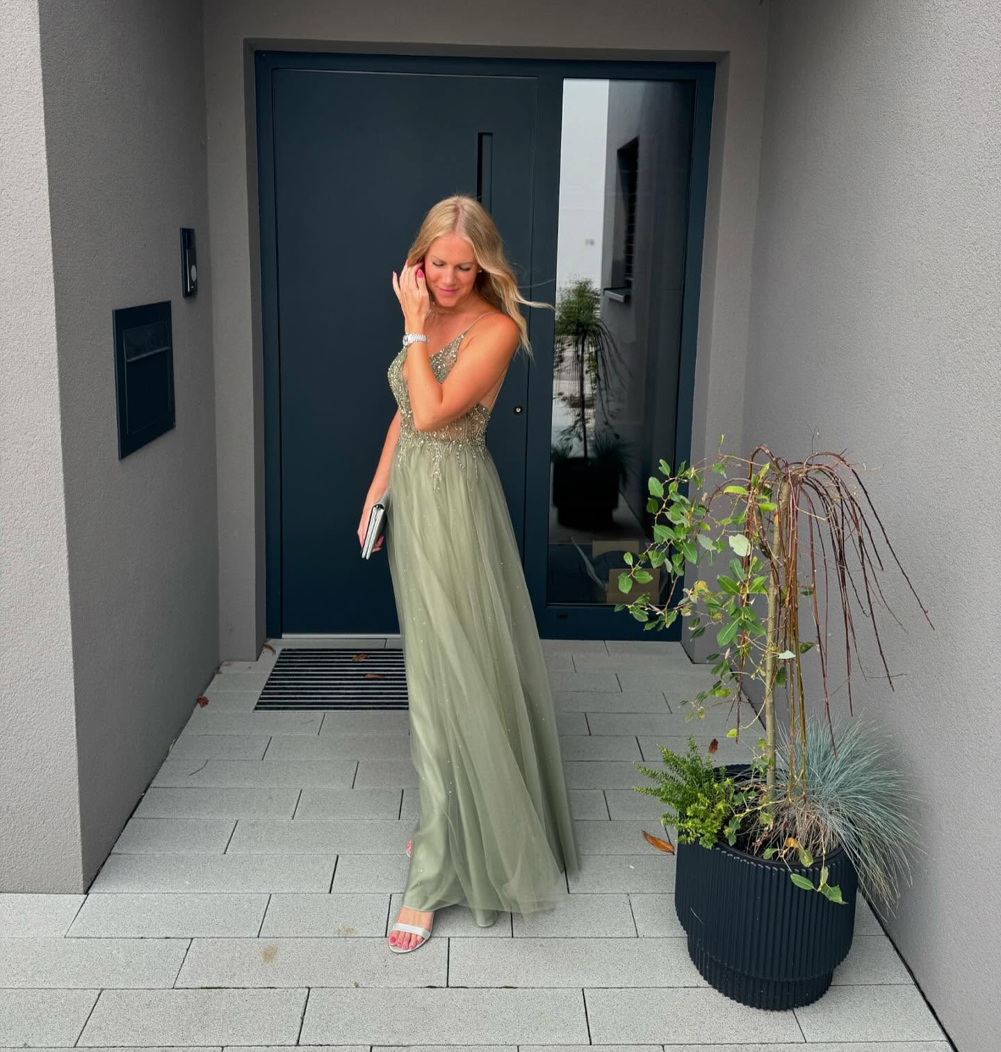 Summer wedding guest in a sage-green embellished maxi dress with silver sandals