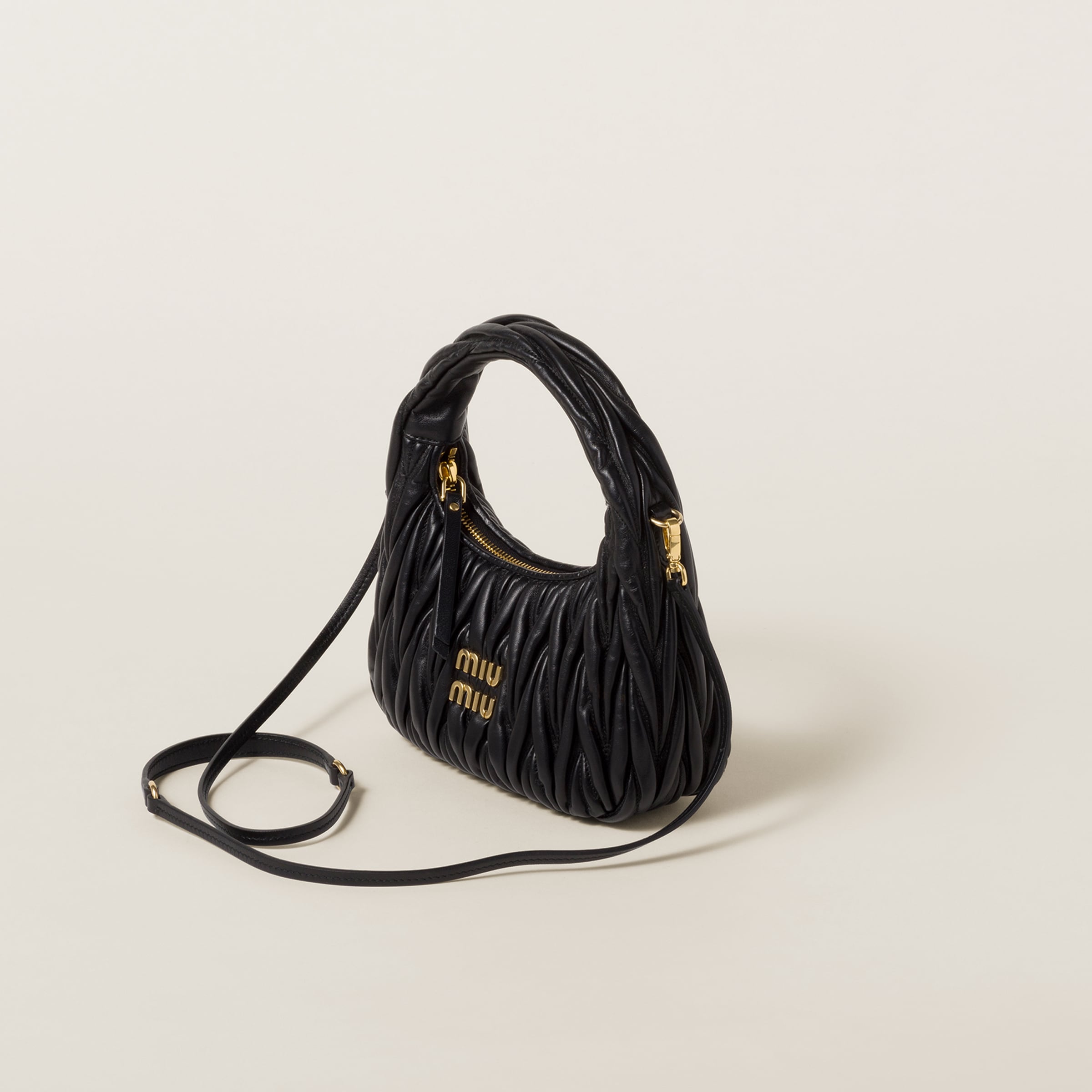Miu Miu Wander bag angled view with leather shoulder strap, gold-tone hardware, zipper closure, and matelasse texture.